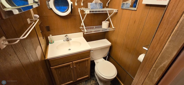 bathroom with vanity, wood walls, and toilet