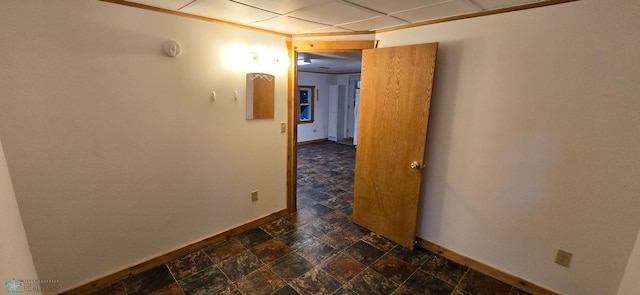 hallway with a paneled ceiling and dark tile patterned flooring