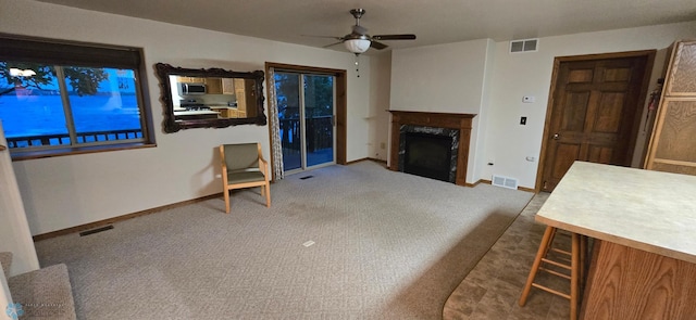 living room featuring carpet, a fireplace, and ceiling fan