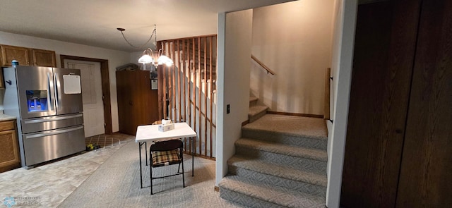 stairway with light carpet and a notable chandelier