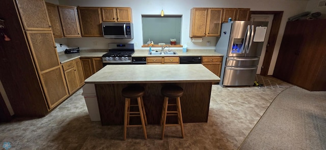 kitchen with a center island, tile patterned floors, appliances with stainless steel finishes, a kitchen breakfast bar, and sink