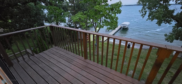 wooden terrace with a boat dock, a water view, and a lawn