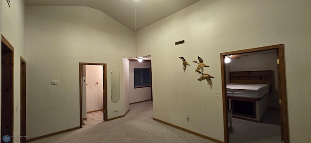 corridor with light carpet and high vaulted ceiling