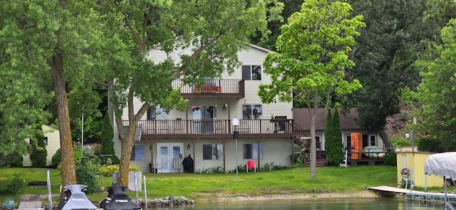 rear view of property with a deck with water view and a lawn