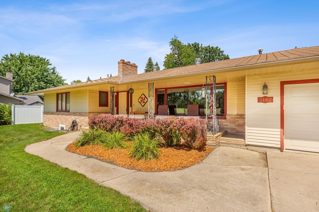 ranch-style home with a garage, covered porch, and a front lawn