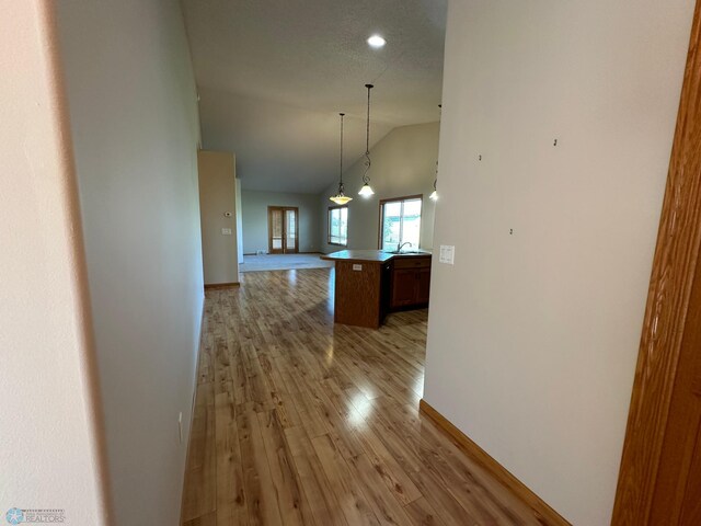 corridor featuring light hardwood / wood-style floors and high vaulted ceiling