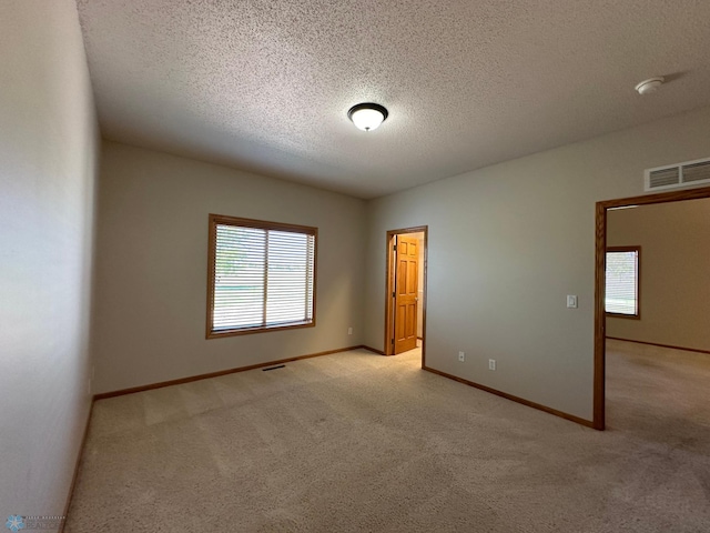 carpeted spare room with a textured ceiling