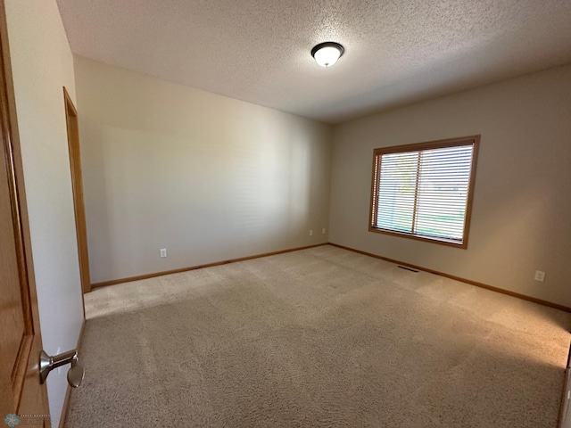 carpeted empty room featuring a textured ceiling