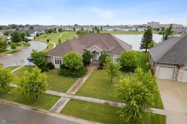 view of front of property featuring a front yard, a garage, and a water view