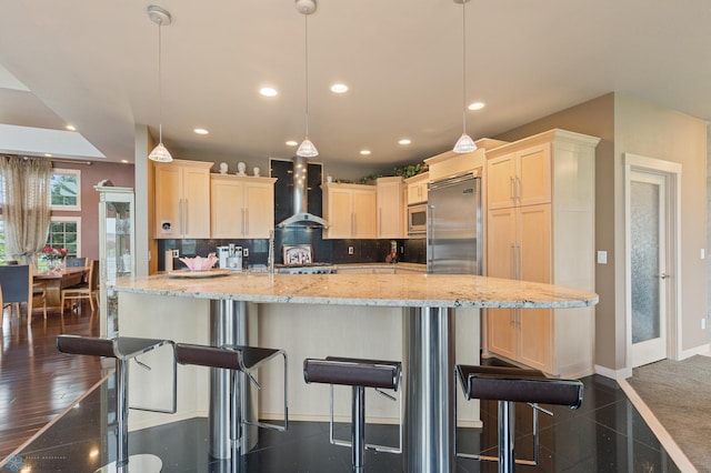 kitchen featuring wall chimney exhaust hood, pendant lighting, and a kitchen bar