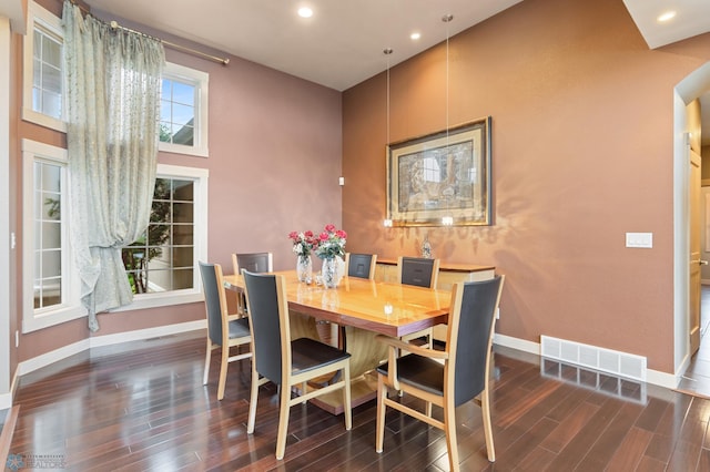 dining room with a high ceiling and dark hardwood / wood-style floors