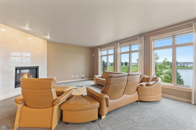 carpeted living room featuring a fireplace and a water view