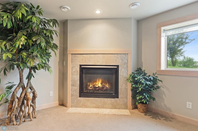 room details featuring a tiled fireplace and carpet flooring