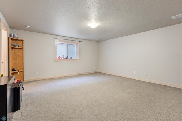 spare room with light colored carpet and a textured ceiling