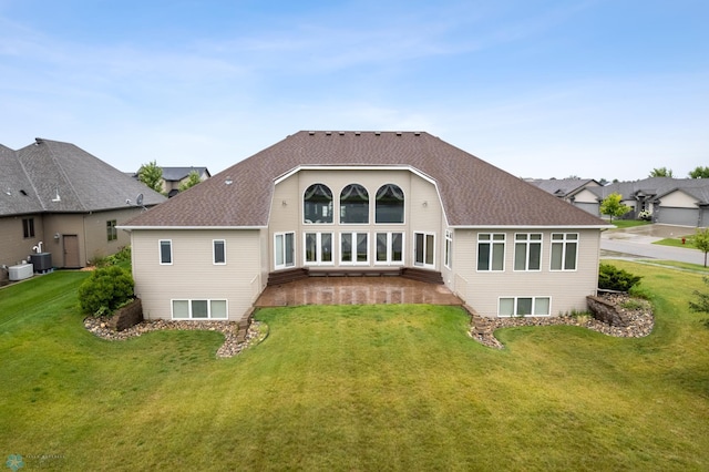 rear view of house with central AC and a lawn