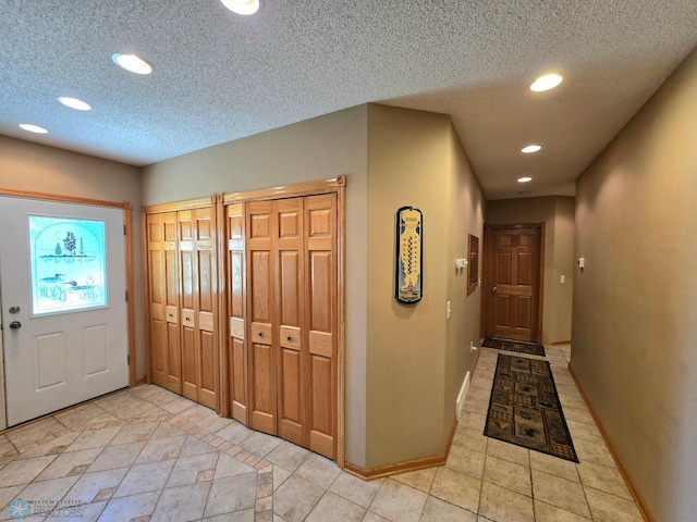 foyer entrance with a textured ceiling and light tile patterned floors