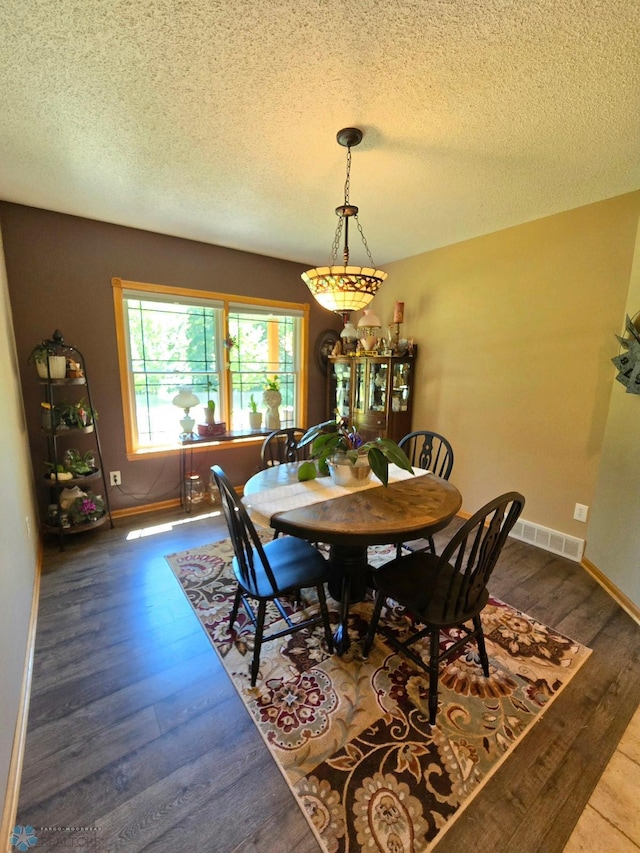 dining area with a textured ceiling and wood-type flooring