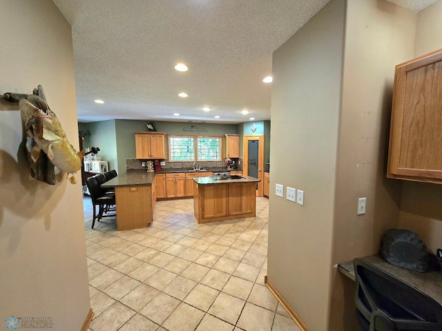 kitchen with light tile patterned flooring, a center island, a kitchen bar, and a textured ceiling