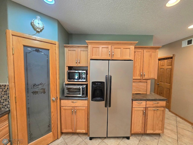 kitchen featuring a textured ceiling, light tile patterned floors, and stainless steel appliances