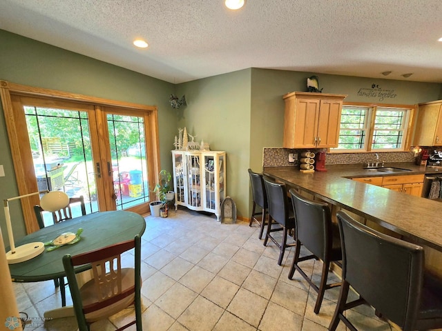 kitchen with sink, a textured ceiling, tasteful backsplash, and light tile patterned floors