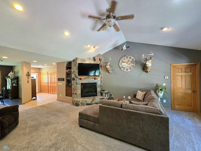 living room featuring lofted ceiling, a textured ceiling, ceiling fan, a fireplace, and light carpet