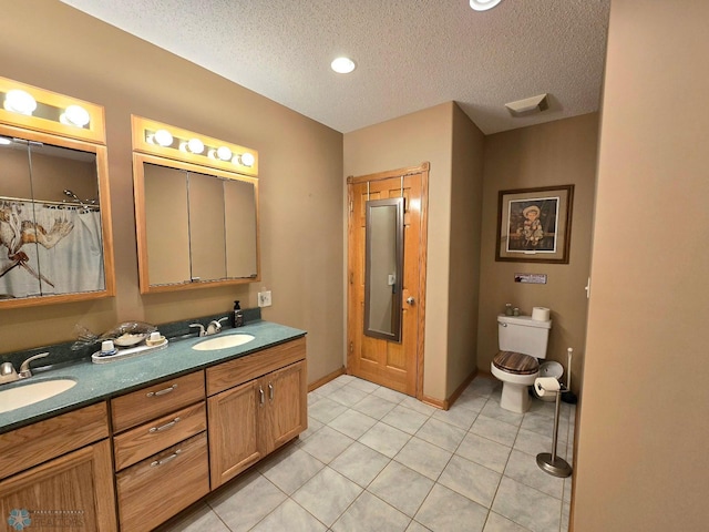 bathroom with dual vanity, tile patterned flooring, toilet, and a textured ceiling