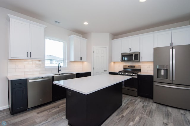 kitchen with light hardwood / wood-style flooring, stainless steel appliances, tasteful backsplash, sink, and a kitchen island