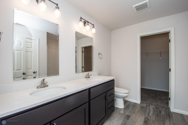 bathroom with dual vanity, toilet, and wood-type flooring