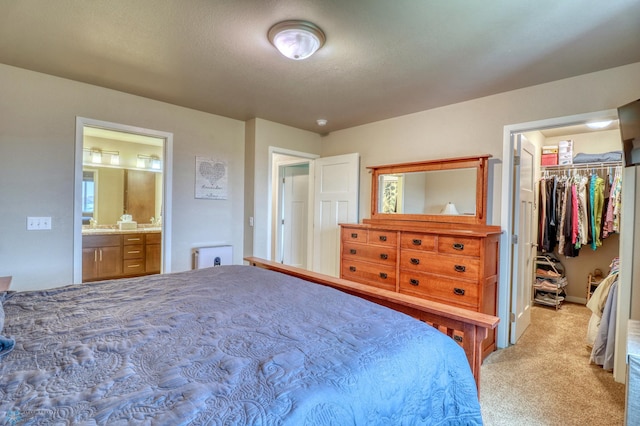 bedroom featuring light carpet, a closet, ensuite bath, and a spacious closet