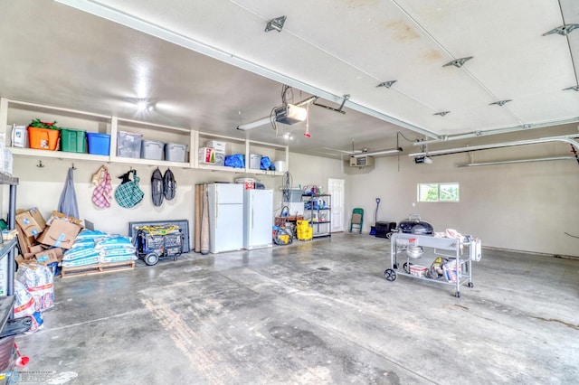 garage featuring white fridge and a garage door opener