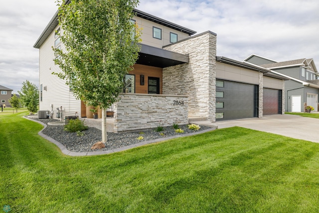 contemporary home featuring a garage, central AC, and a front lawn