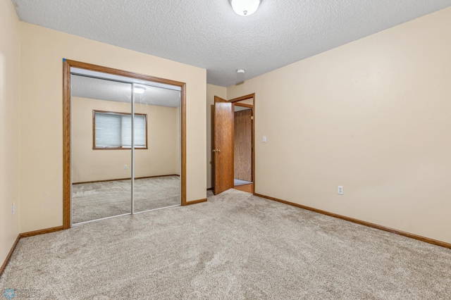 unfurnished bedroom featuring light colored carpet, a closet, and a textured ceiling