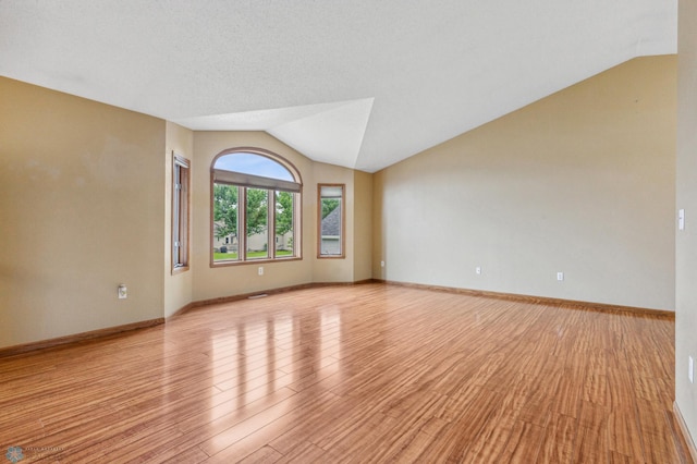 unfurnished room with vaulted ceiling and light wood-type flooring