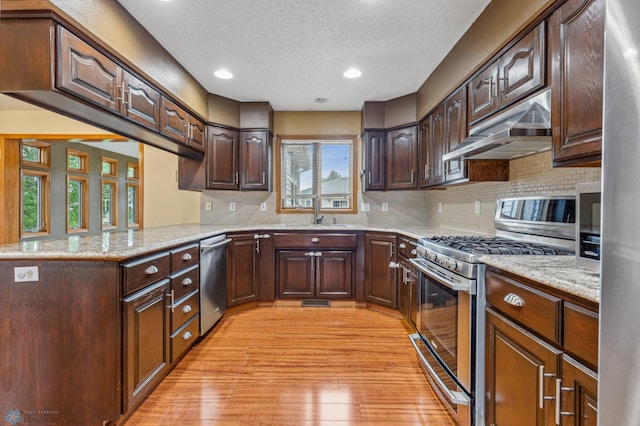 kitchen with plenty of natural light, light hardwood / wood-style flooring, decorative backsplash, and range with gas stovetop