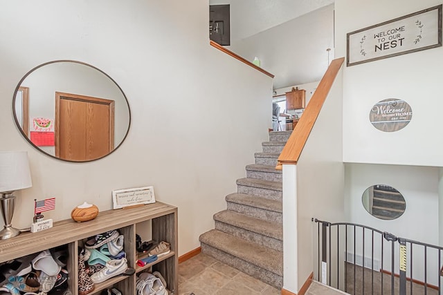 stairway with light tile patterned floors and electric panel