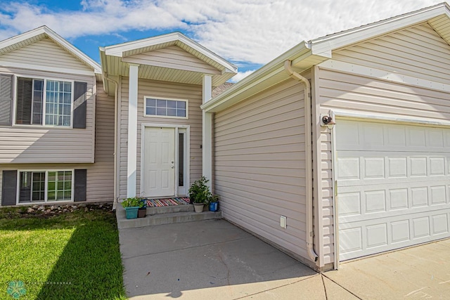 doorway to property with a yard and a garage