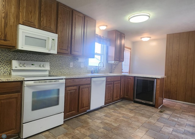 kitchen with light tile patterned floors, wine cooler, backsplash, white appliances, and sink