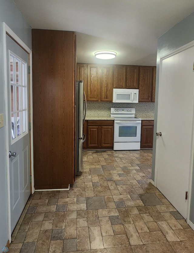 kitchen featuring white appliances, decorative backsplash, and light tile patterned flooring