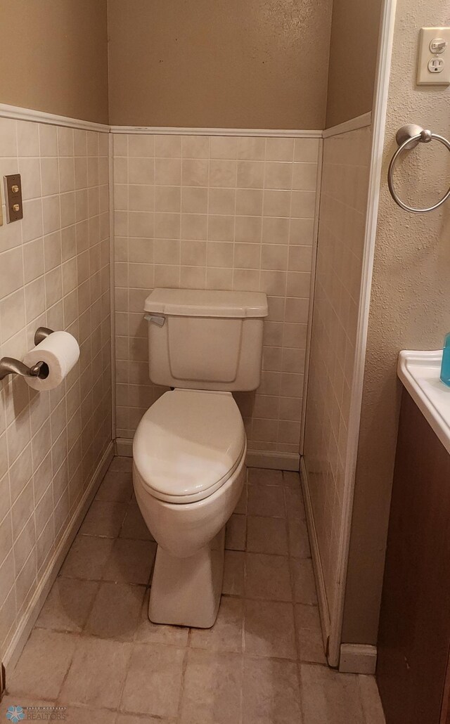 bathroom with tile walls, vanity, tile patterned flooring, and toilet