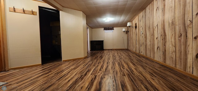 basement with wooden walls and dark wood-type flooring