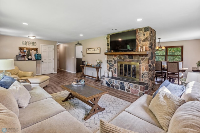 living room featuring a notable chandelier, a stone fireplace, and wood-type flooring