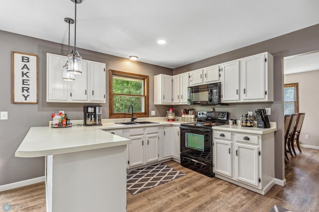 kitchen with white cabinetry, kitchen peninsula, black appliances, pendant lighting, and sink