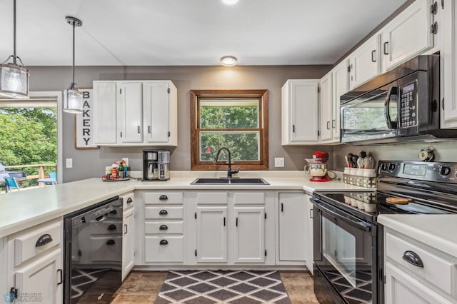 kitchen featuring white cabinets, hanging light fixtures, black appliances, light wood-type flooring, and sink