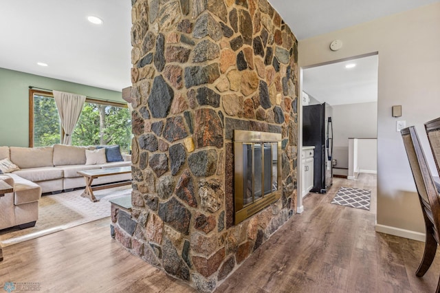 living room featuring hardwood / wood-style flooring and a stone fireplace