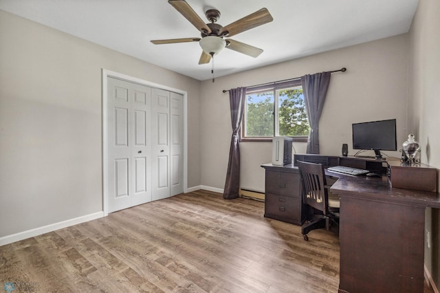 office space featuring ceiling fan, a baseboard heating unit, and light hardwood / wood-style floors