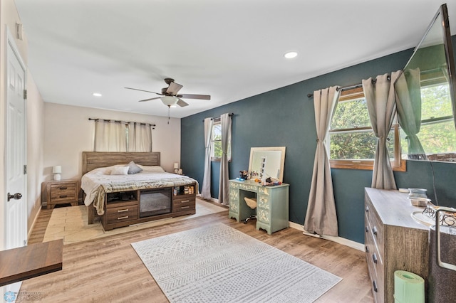 bedroom featuring light hardwood / wood-style flooring, ceiling fan, and multiple windows