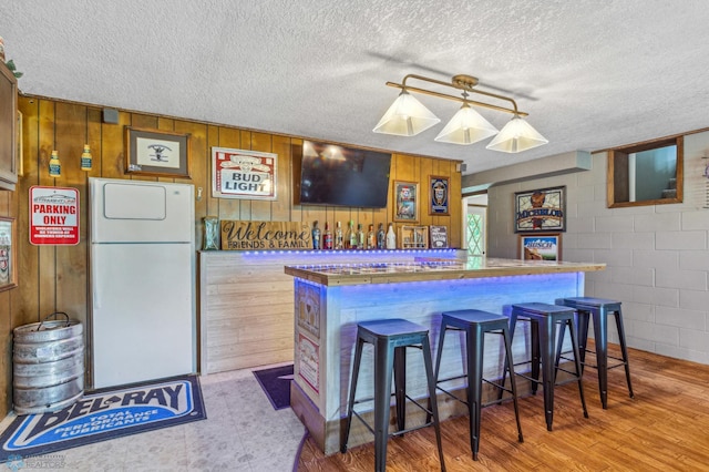 kitchen featuring a textured ceiling, hardwood / wood-style flooring, and white fridge