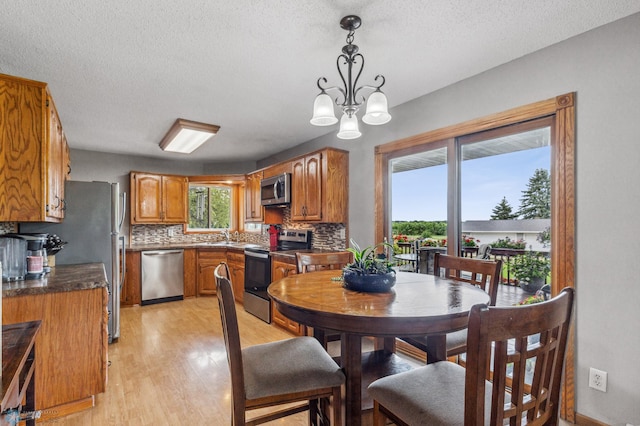 dining space featuring light hardwood / wood-style floors, a textured ceiling, and a chandelier