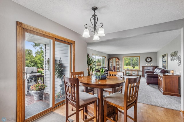 dining area with a textured ceiling, a chandelier, and light wood-type flooring