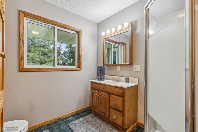 bathroom with a textured ceiling, toilet, tile patterned floors, walk in shower, and vanity